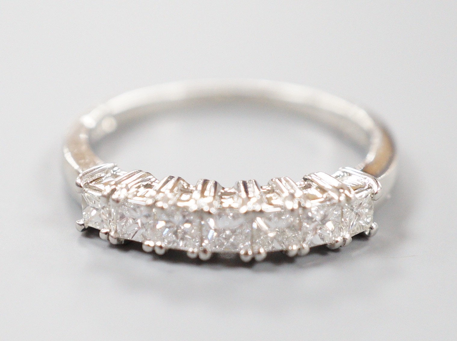 A modern platinum and seven stone princess cut diamond set half hoop ring, size M/N, gross weight 4 grams